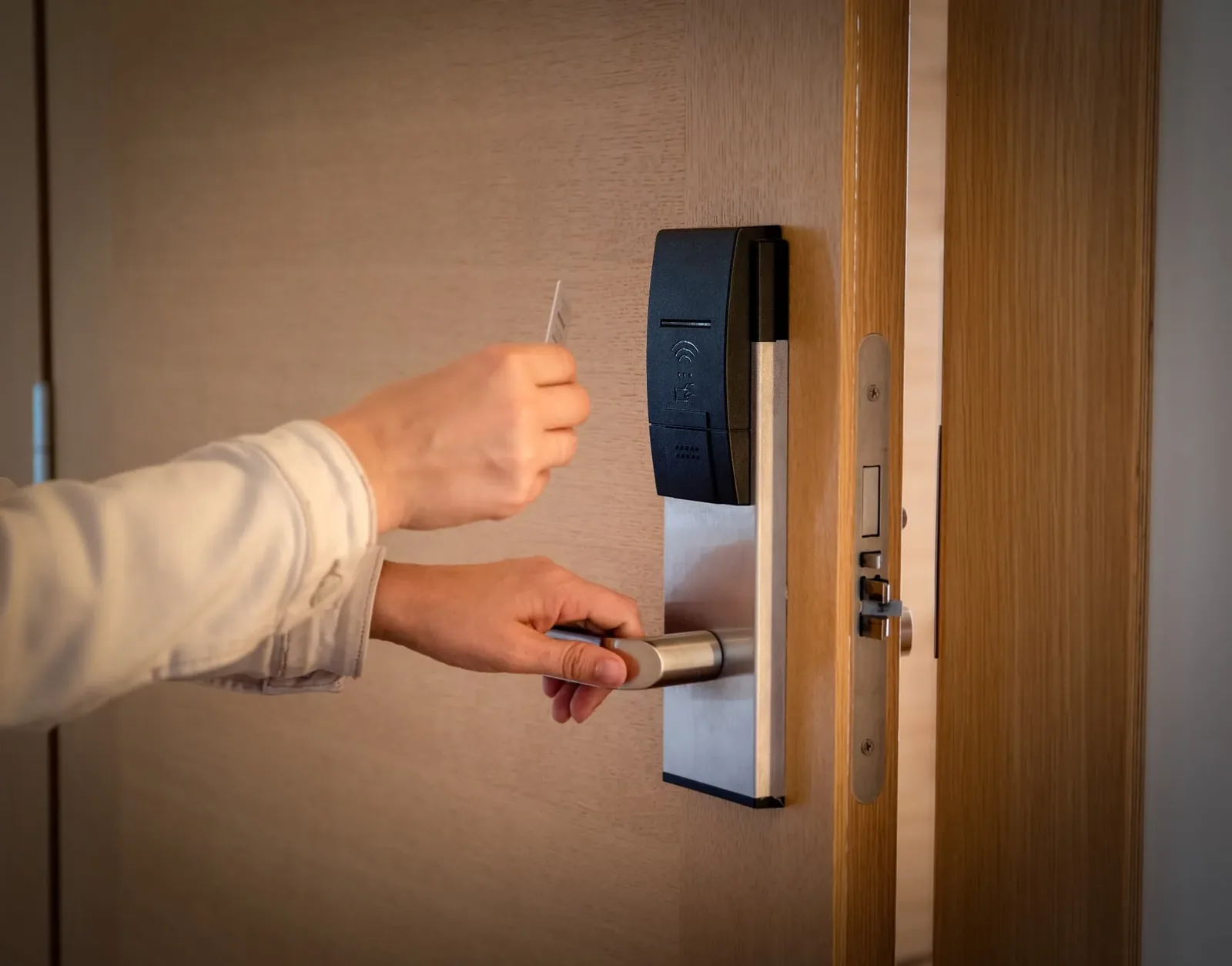 Person unlocking a wooden door with an RFID card on an electronic lock