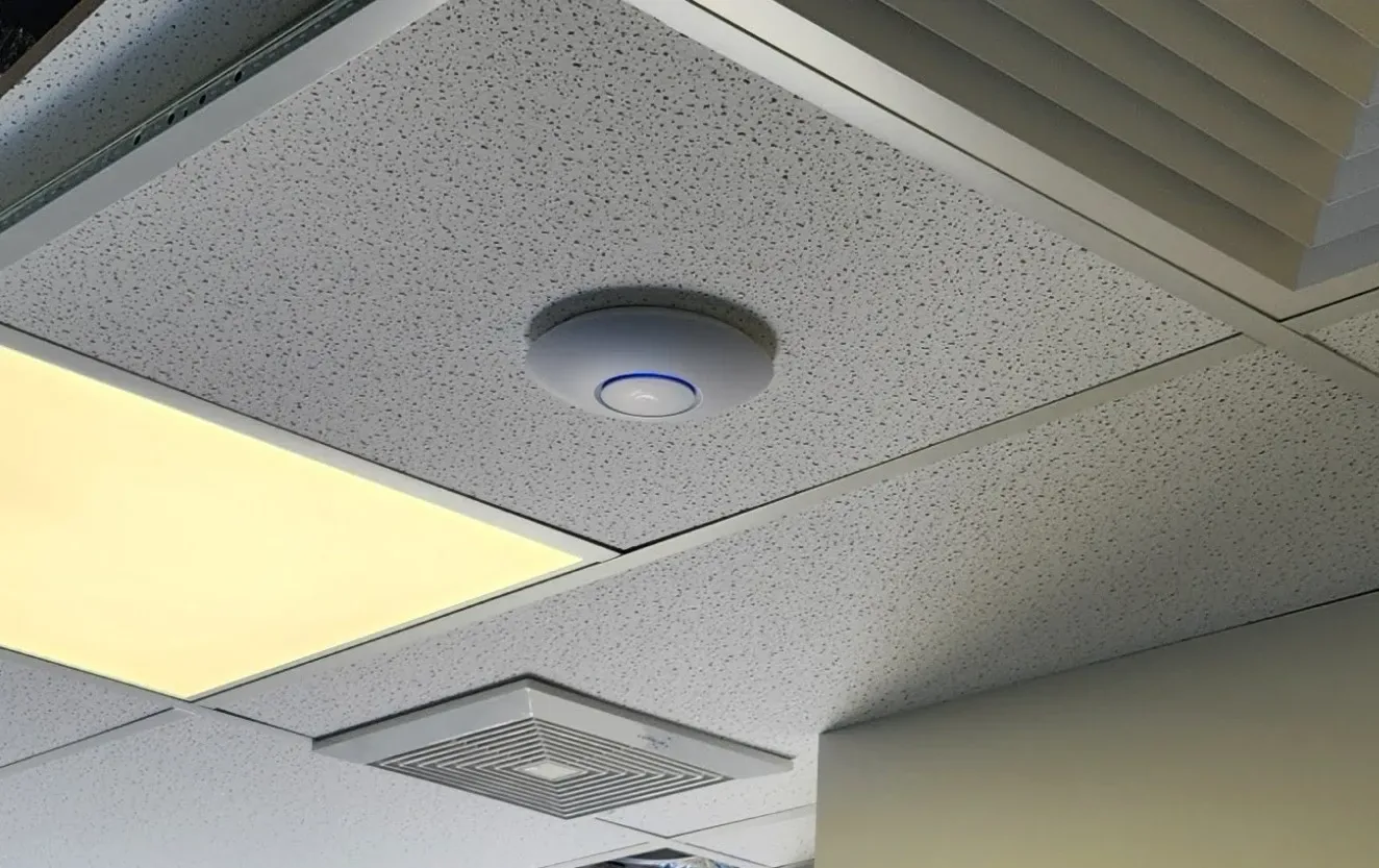 Ubiquiti UniFi access point on a drop ceiling in a commercial office