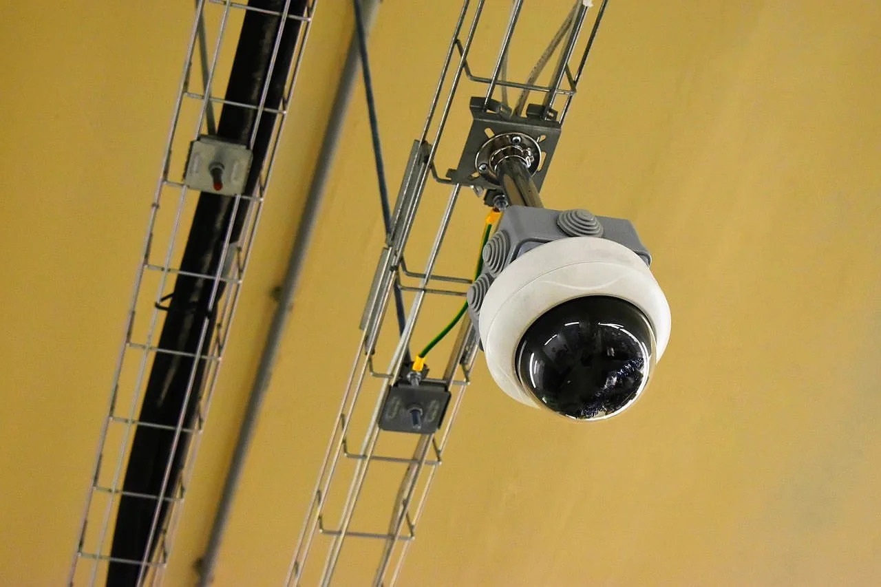 Dome camera on a steel truss beneath a yellow ceiling