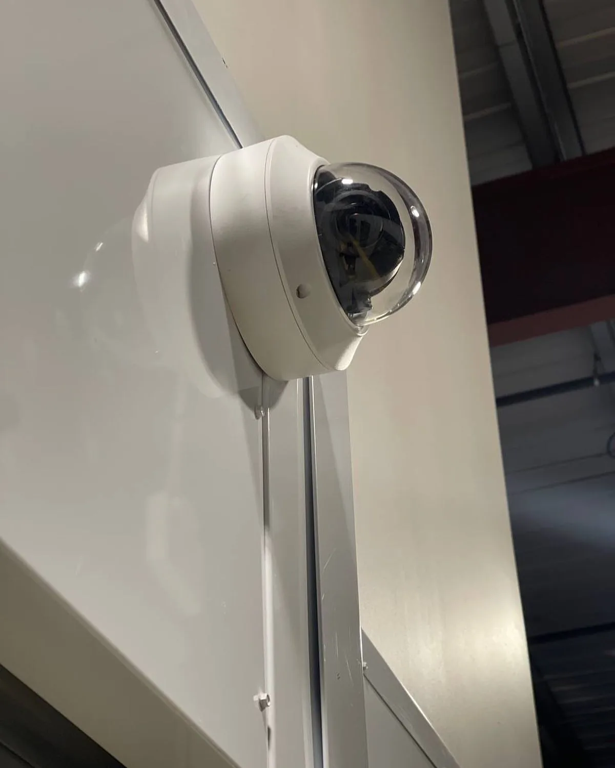Dome camera on a white column with conduit inside a commercial space