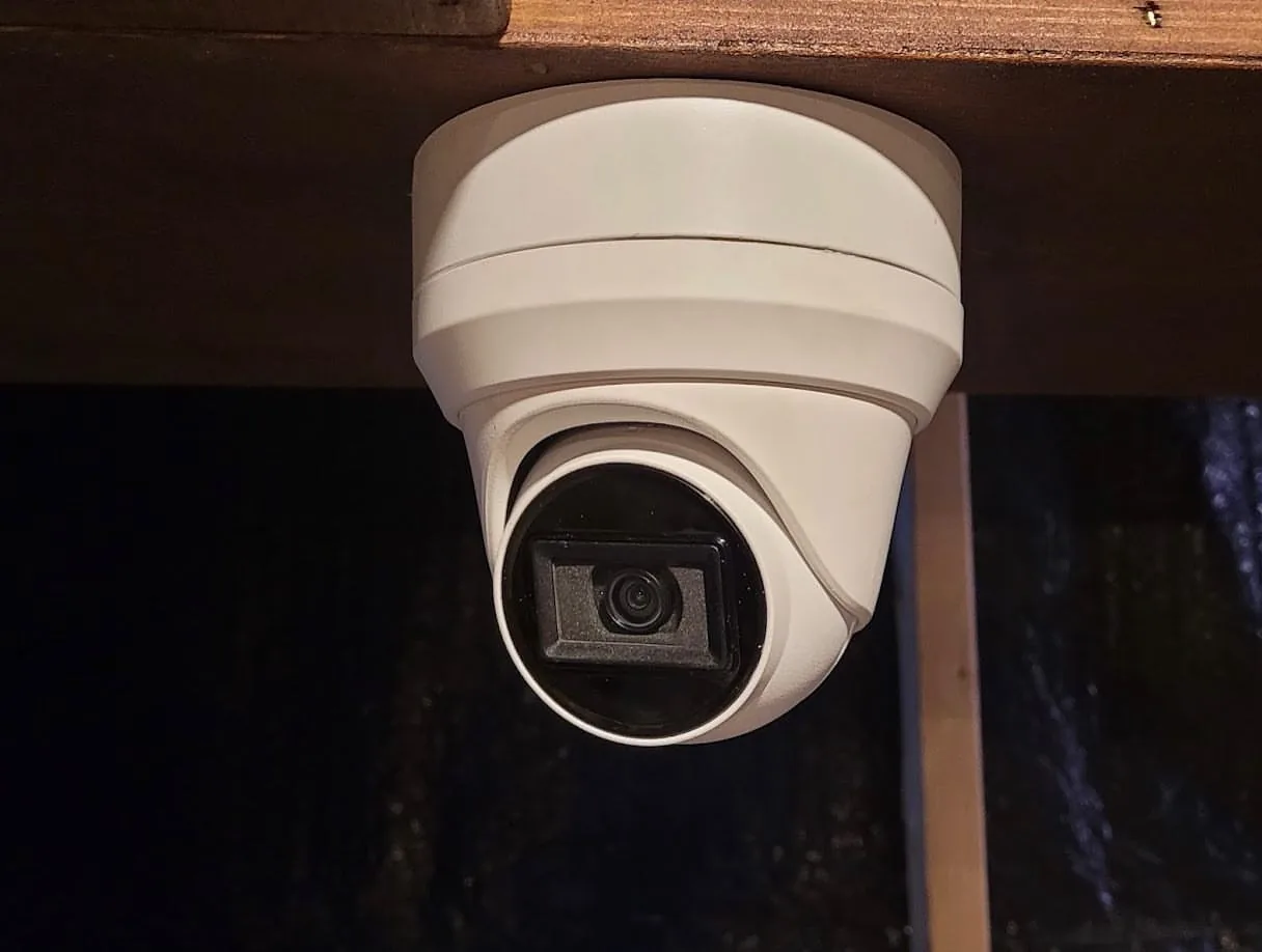 White turret camera under a wood porch ceiling