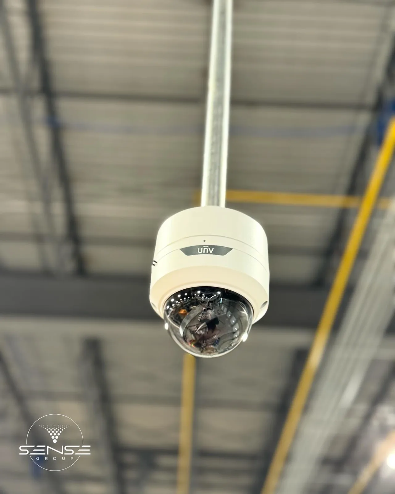 UNV dome camera on a pole mount under a warehouse ceiling