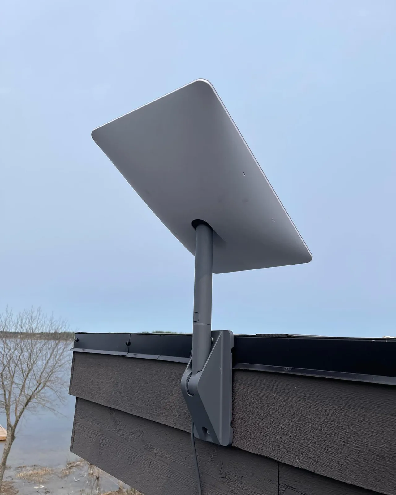 Starlink dish on a roof edge overlooking a lake in Springwater