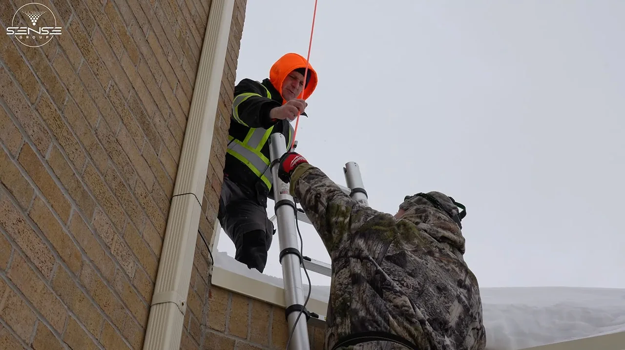 Installer on a ladder secured with a rope at the church