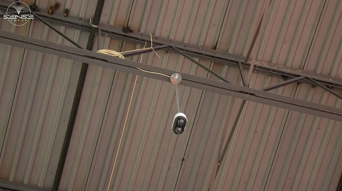 Bullet camera on a steel beam under a high industrial warehouse ceiling
