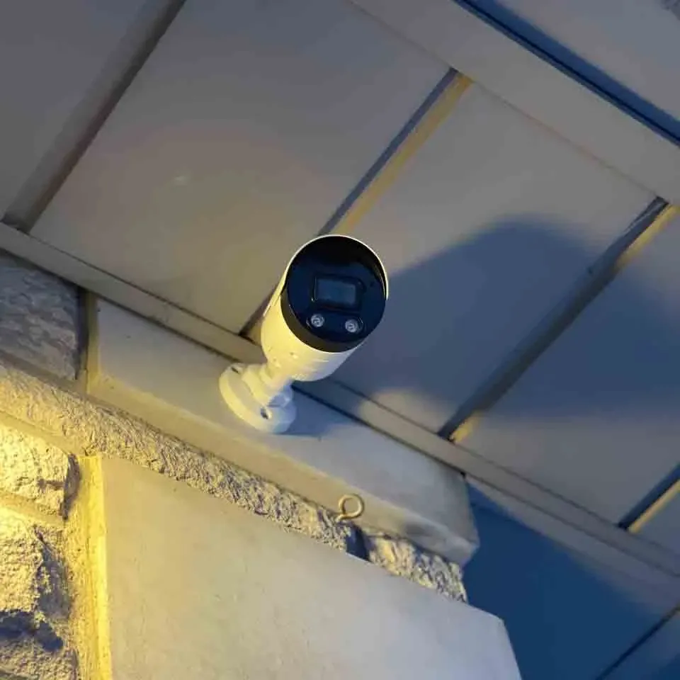 White bullet camera mounted under the soffit of a house exterior