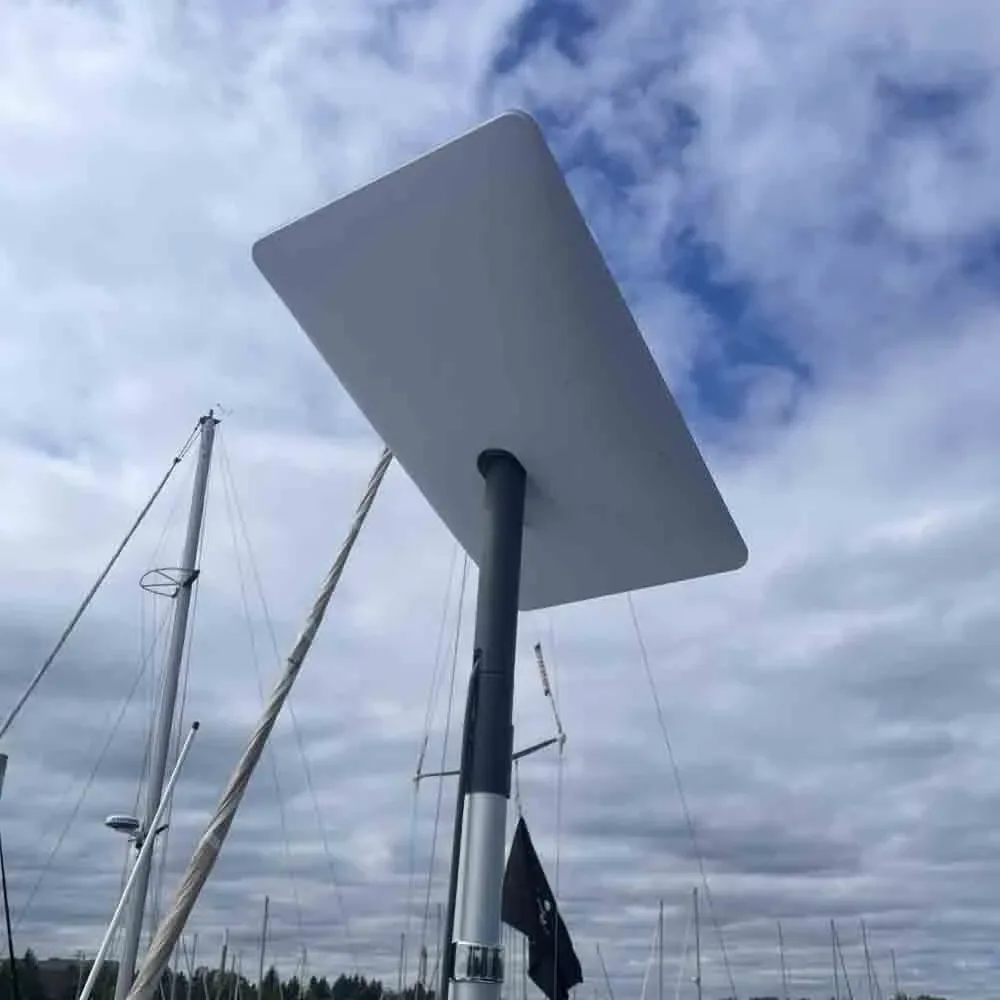 Starlink dish on a sailboat mast against a cloudy sky