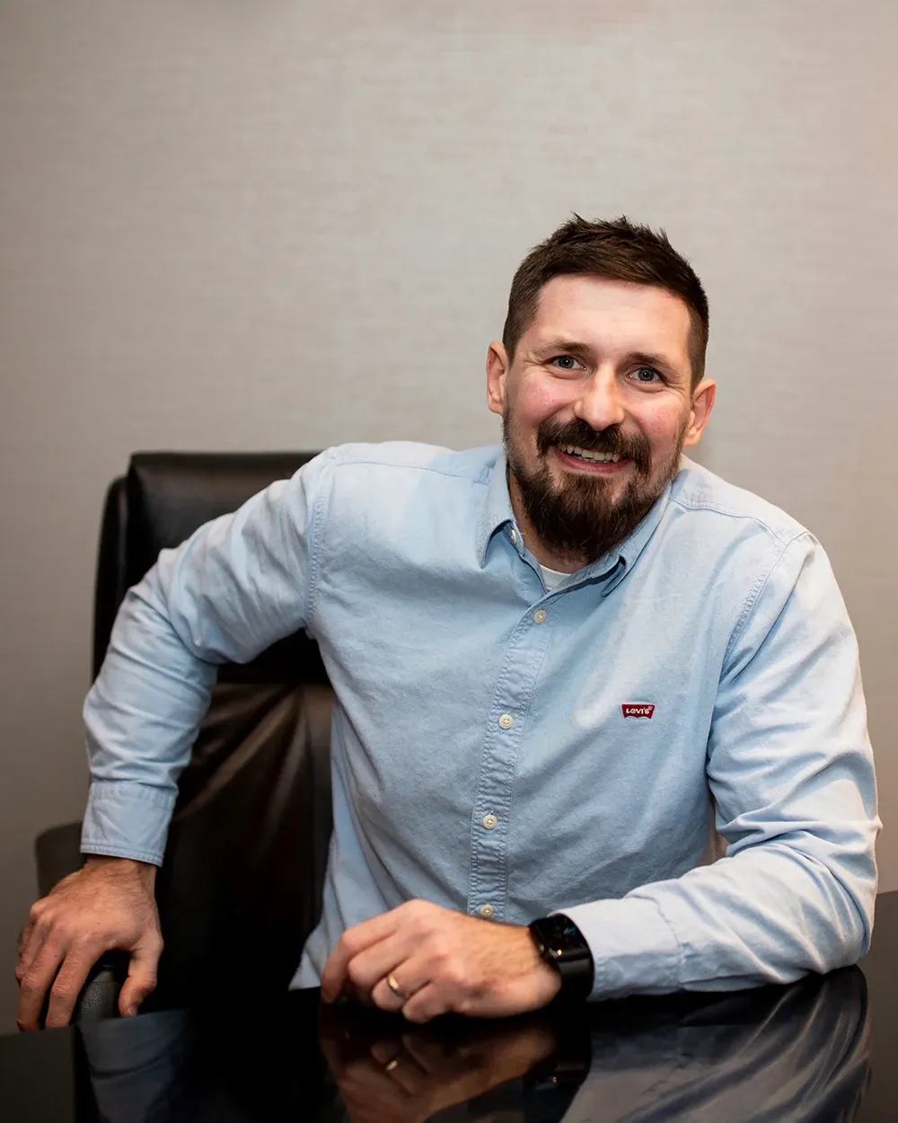 Vitaly Sukhina, founder, smiling at a desk in a light blue shirt