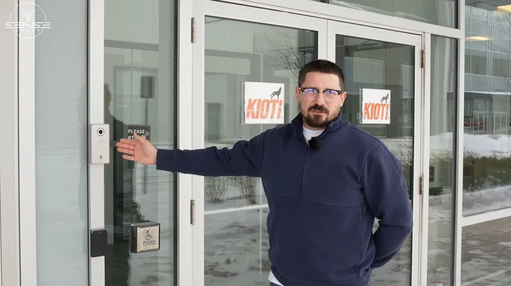 Technician demonstrating commercial video intercom and access control system at warehouse entrance in Milton Ontario