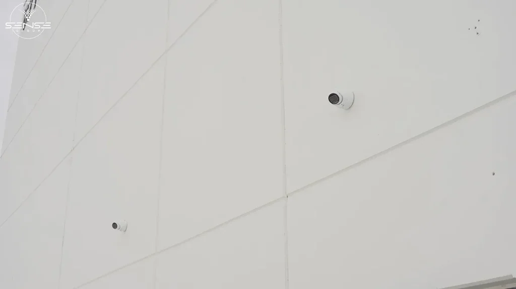 Two outdoor bullet security cameras installed on white commercial warehouse wall in Ontario for perimeter surveillance